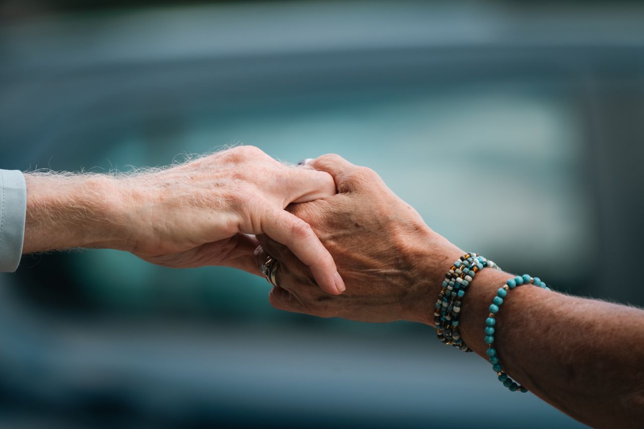 A heartfelt image of two elderly individuals holding hands, symbolizing love and support.